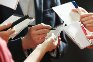 Elegant man signing autograph in notebook on dark background